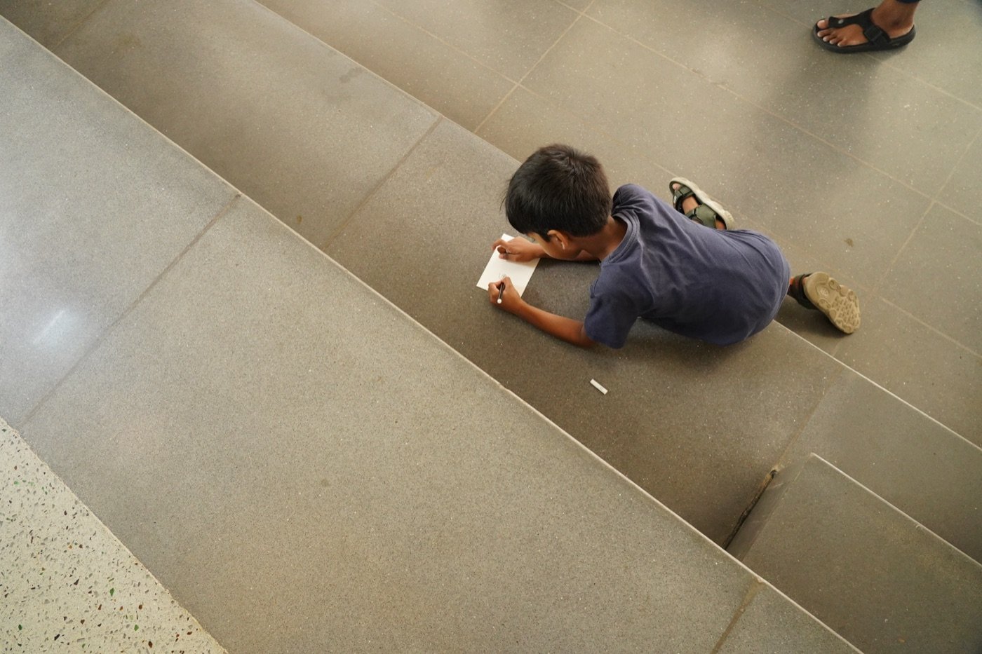A kid sketching on the steps